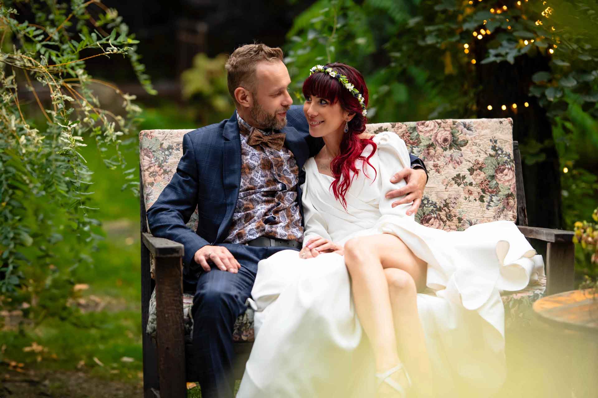 Młoda para siedzi na ławce przytuleni i wpatrzeni w siebie