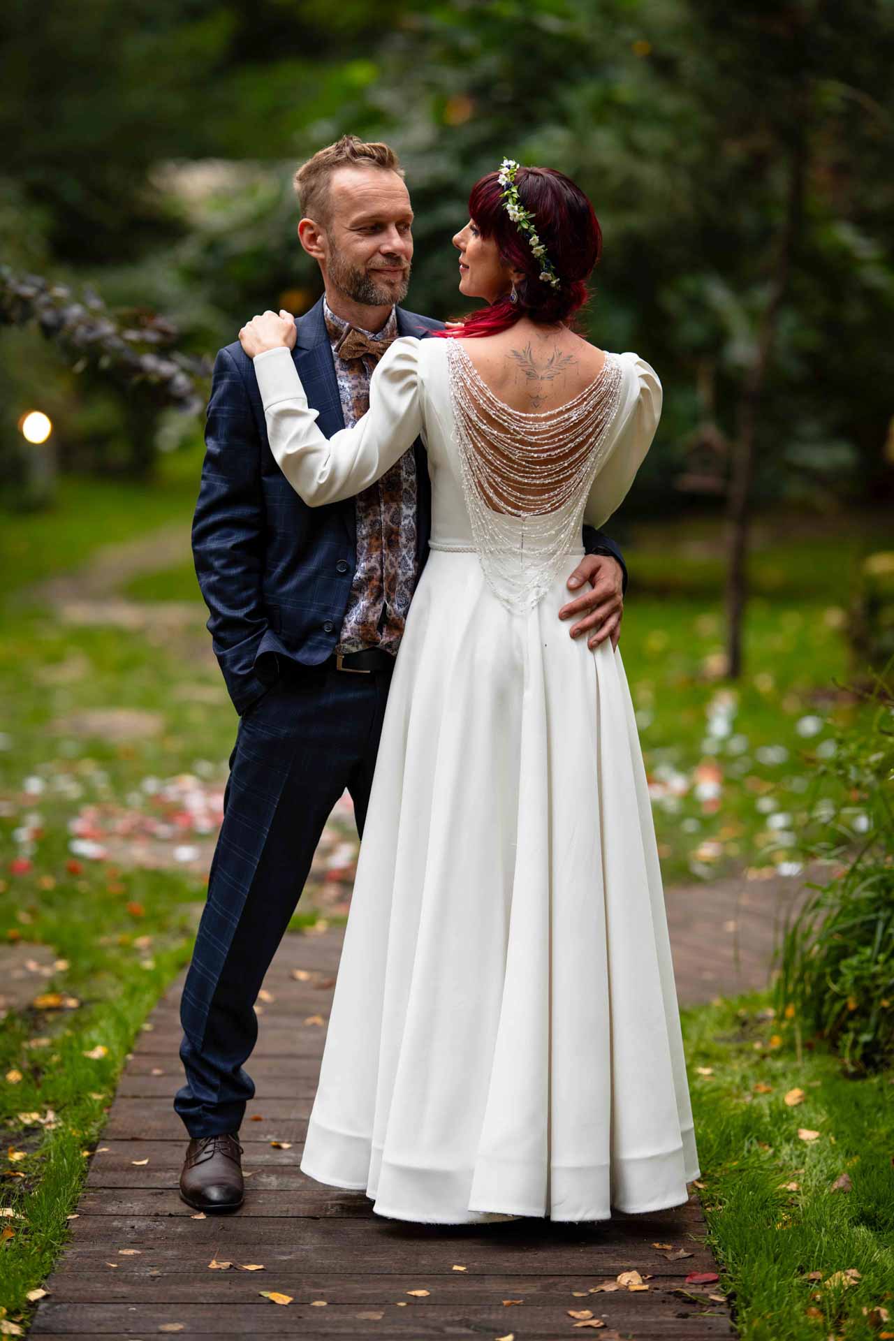 Ślub w plenerze Kasia i Tomek Para stoi obok siebie. Pan młody patrzy sie na małżonkę i trzyma rękę na jej biodrze