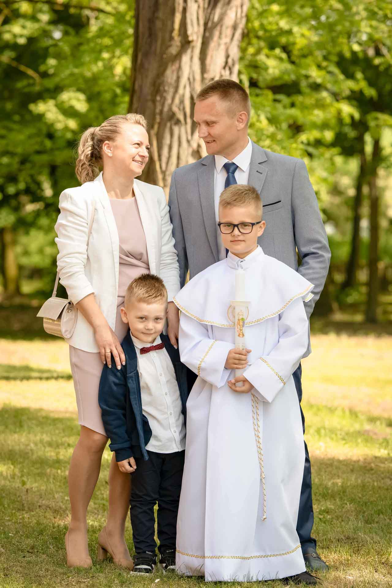 Portret chłopca w stroju do Komunii Świętej wraz z rodzicami i bratem zdjęcie rodziny w parku